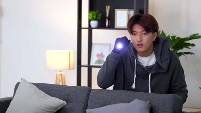Suspicious Man in Hoodie Using Flashlight During Indoor Burglary Scene