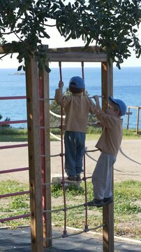 Children boys climbing playground structures, demonstrating coordination, balance, and physical development. Concept of learning through play. 