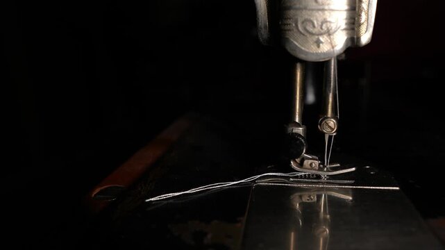 A seamstress works on an old sewing machine, a seamstress works in a sewing workshop