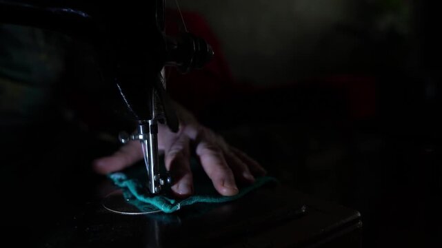 Old sewing machine in use at home, sewing on a vintage machine, dark background