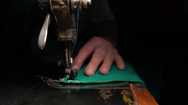 Old sewing machine in use at home, sewing on a vintage machine, seamstress working, dark background