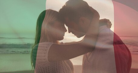 Obraz premium Embracing couple in knit top, red jacket leaning heads at beach wet sand, with color overlay