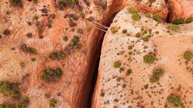 Dramatic aerial drone view looking down into a steep and narrow rock canyon gorge.