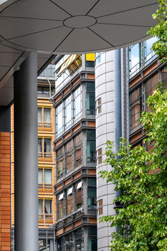 Street walkway perspective through modern urban architecture with office columns and canopy as trees soften the scene and add depth