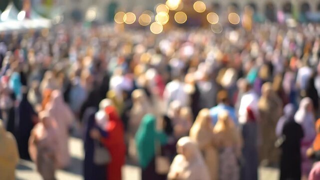A large, blurred crowd of people gathered outdoors, many wearing head coverings, suggesting a public event or religious assembly.