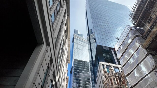 London cityscape contrasting modern glass skyscrapers with traditional architecture and a building under renovation, showing urban development and the city evolution