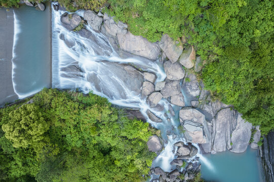 Aerial View of a Serene Mountain River Cascading Over Granite Boulders Amidst Lush Green Forest