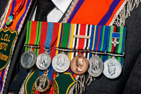 Row of Medals including a George Cross worn by a veteran with an Orange Sash on 12th July Orange Day parade