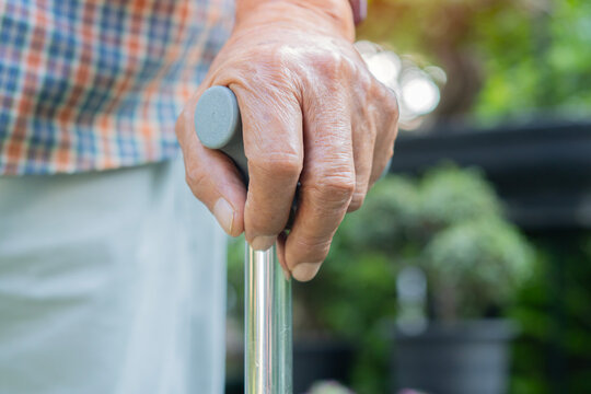 Walking stick, hand and senior man in the garden at home with dementia in nursing facility
