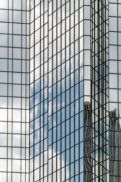 Glass architecture detail on modern facade where grid windows hold reflections and symmetry forming an abstract pattern across the surface