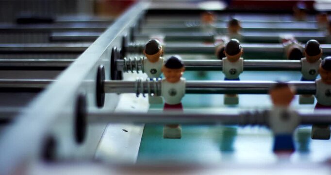 Close-up of a table soccer game with plastic players on metal rods in a bright office lounge