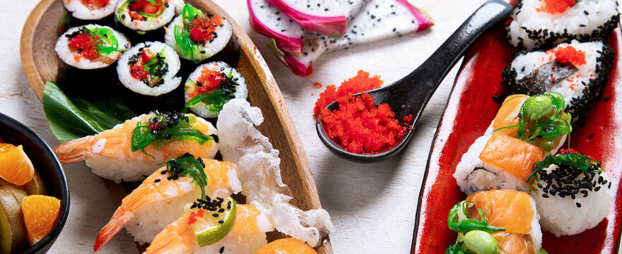 A table with Asian food, sushi, rolls, desserts.