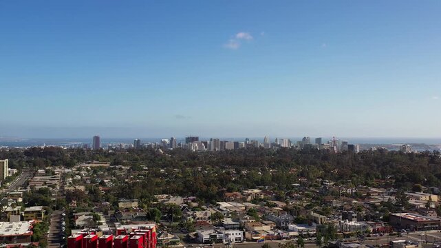 Drone pulling back over North Park at 5PM with camera facing toward downtown San Diego skyline and urban landscape.