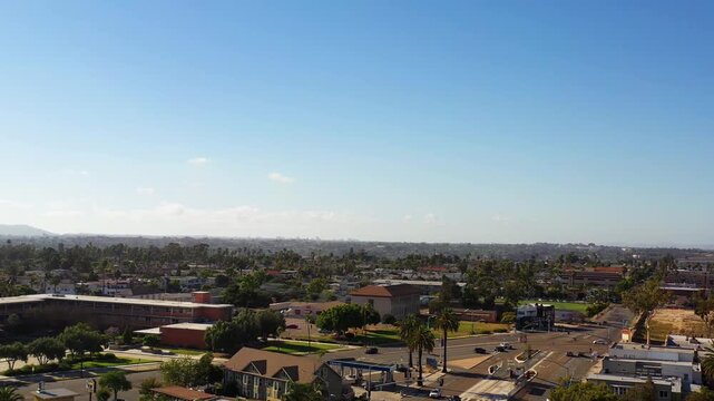 Drone pulling back over North Park at 5PM with camera facing toward downtown San Diego skyline and urban landscape.