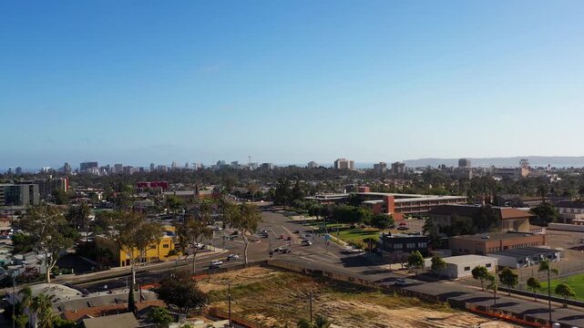 Drone flying over North Park at 5PM with mountains in the distance and downtown San Diego skyline ahead.