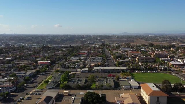 Drone flying over North Park at 5PM with mountains in the distance and downtown San Diego skyline ahead.
