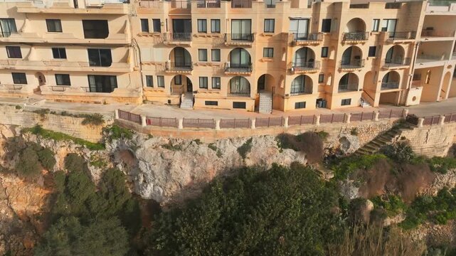 Aerial Drone flight revealing ancient agriculture terraces and historic houses to modern Gozo, Zebbug, Malta Historic Cityscape with resorts, hotels, preserved architecture. Traveling time concept