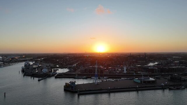 Harbor crane silhouette with sunrise above quiet town skyline