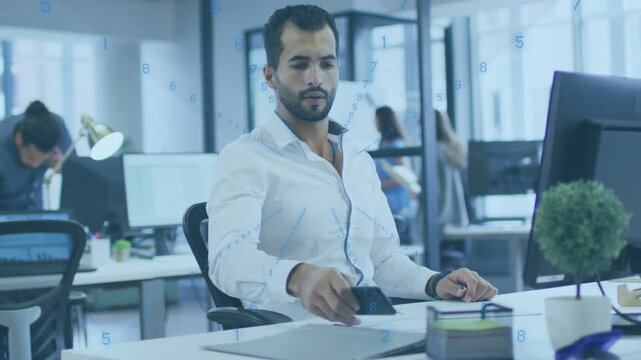 Adjusting desk items, male worker in white shirt picking up phone at open office, checking messages