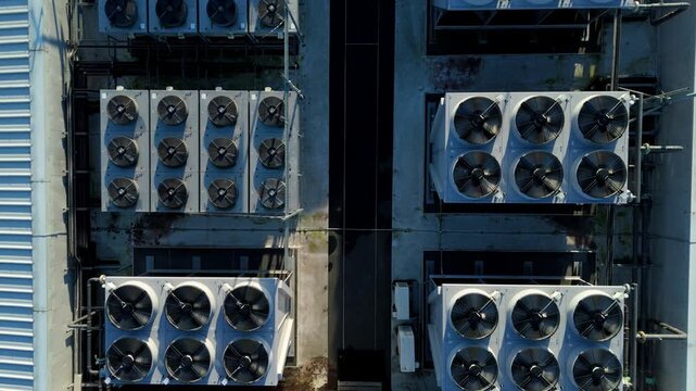 Close up drone flight over rotating rooftop cooling turbines on a high-tech data storage and processing center