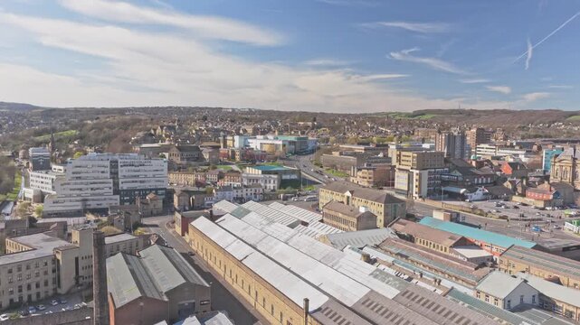Historic textile mill with sawtooth roof near Queensgate Colne Road Huddersfield Kirklees West Yorkshire England United Kingdom with chimney and industrial buildings, drone ascent shot