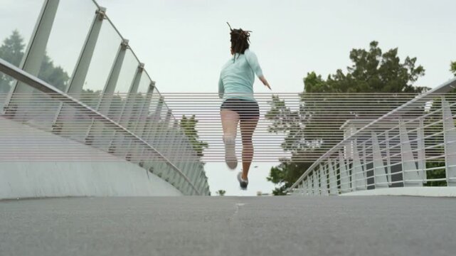 Vertical video: Starting stride near camera woman running pumping arms crossing bridge training