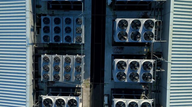 Close up aerial view of industrial cooling fans rotating on the rooftop of a massive data center