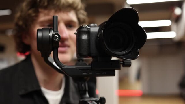 Videographer actively shoots video using camera on stabilizer focusing on smooth motion control steady framing and professional filming process in indoor studio environment creating dynamic content