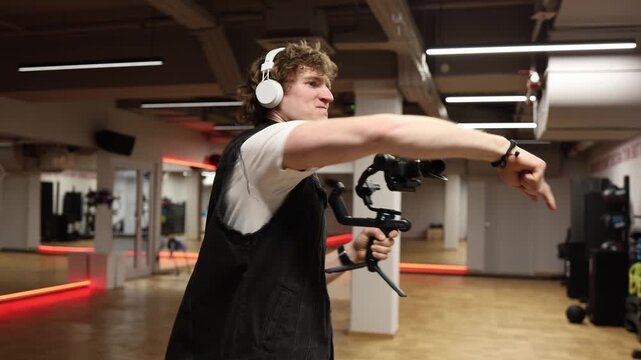 Videographer celebrates successful shoot raising hands with camera on gimbal expressing эмоtion and satisfaction after completing filming project in professional indoor studio environment