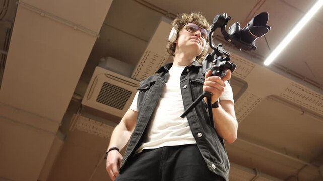 Videographer adjusts gimbal settings before filming focusing on balance control and camera stability preparing equipment for smooth motion and precise cinematic recording in indoor studio space