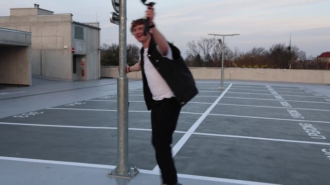 Videographer rides on rollerblades spinning around pole celebrating finished project expressing freedom and excitement after shooting dynamic movement and positive creative energy