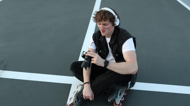 Young photographer sits on rollerblades and reviews photos on camera screen focused on results creative process hobby photography self analysis learning improvement and calm mood