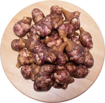 Fresh Jerusalem artichoke pile on round wooden board top view isolated on transparent background, PNG