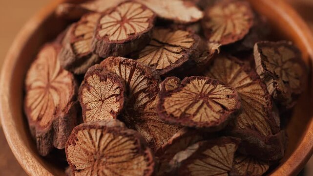 Macro rotating shot of root slices with distinct circular patterns. Strong natural texture emphasizes botanical detail and traditional medicinal use.