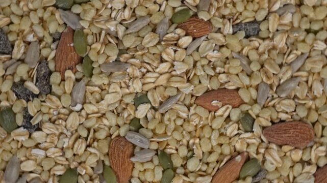 Top view of rotating dry granola cereal texture background with assorted nuts and seeds