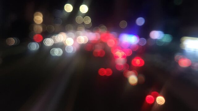 Defocused city traffic lights at night with cars passing by