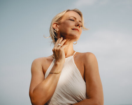Elegant woman wearing luxurious gold jewelry with serene outdoor background