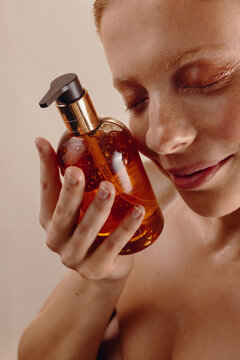 Woman holding amber glass serum bottle close to face