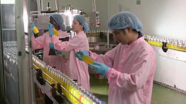 Food females and male factory workers inspecting nutrition drink processing on conveyor belt in food manufacturing factory 