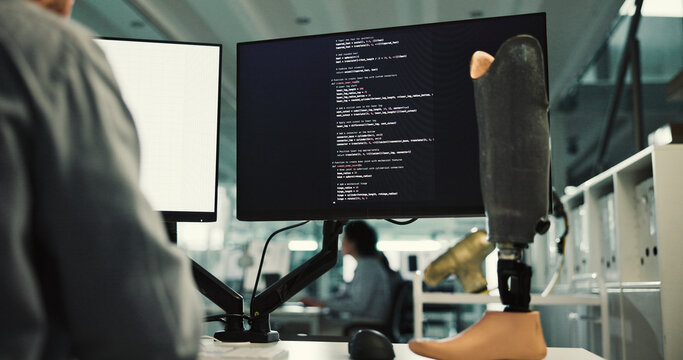 Person, computer screen and programming with prosthetic leg for robotic development in laboratory. Programmer, developer or biomedical engineer with artificial limb or 3D model for code or design