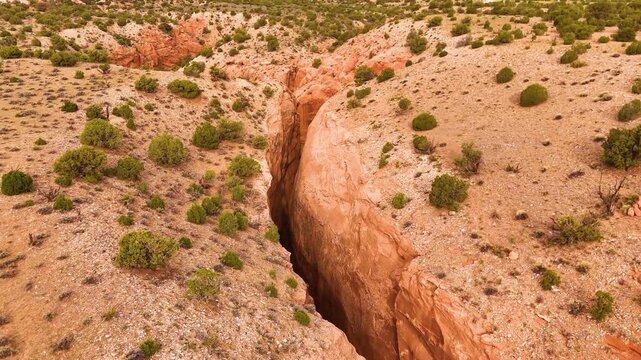 Aerial view of a deep narrow gorge within a vast red rock canyon landscape.