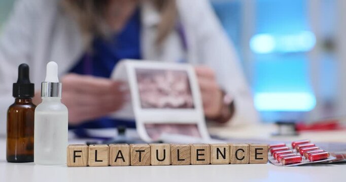 Wooden blocks spell word Flatulence near bottles and tablets on desk. Doctor reads report recommending diet steps while adjusting medicine dose