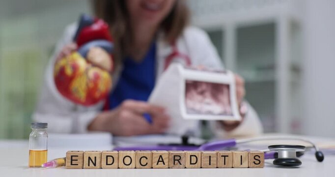 Text Endocarditis on cubes with vial and stethoscope on doctor workplace. Female cardiologist analyzes patient heart ultrasound scans in hospital
