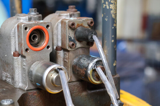 Close up of solenoid valves mounted on a transmission control valve body. Detail of O-ring seals and electrical wiring for heavy machinery hydraulic control system.