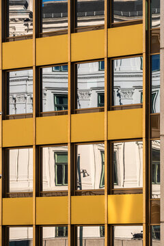 Modern building facade with yellow windows in a grid shows abstract architecture pattern and reflection as a bright textured background