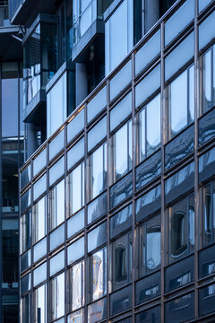 Modern architecture facade of a building uses blue glass windows in a grid pattern with reflection for abstract symmetry and texture