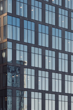 Modern reflection on glass windows of an architecture building facade showing a vertical grid pattern as abstract geometric texture