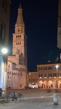 Modena, italy, april 11, 2026. Magnificent view of the ghirlandina tower and modena cathedral in piazza grande, italy. Historical romanic architecture glowing at night