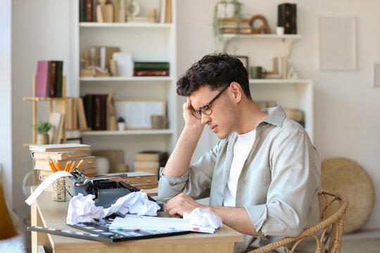 Stressed male screenwriter writing script at table in office