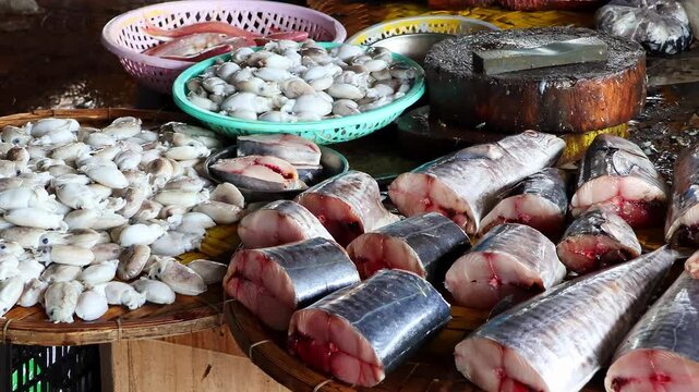 Asian fish market seafood close up. Raw fish cuts and assorted shellfish displayed on traditional wet counter, view of fresh marine products at local trading stall.